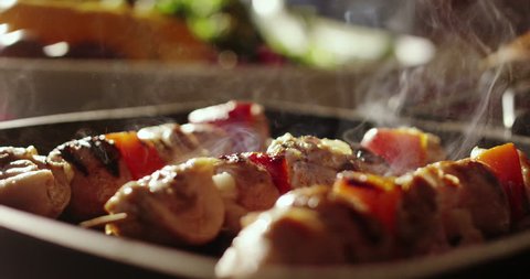 cinemagraph of skewers of meat with vegetables cooked on a spit in a pan