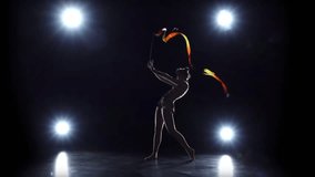 Gymnast with the ribbon in her hands doing acrobatic moves. Black background. Light rear. Slow motion - Powered by Shutterstock - Get 15% off with code: PIKWIZARD15