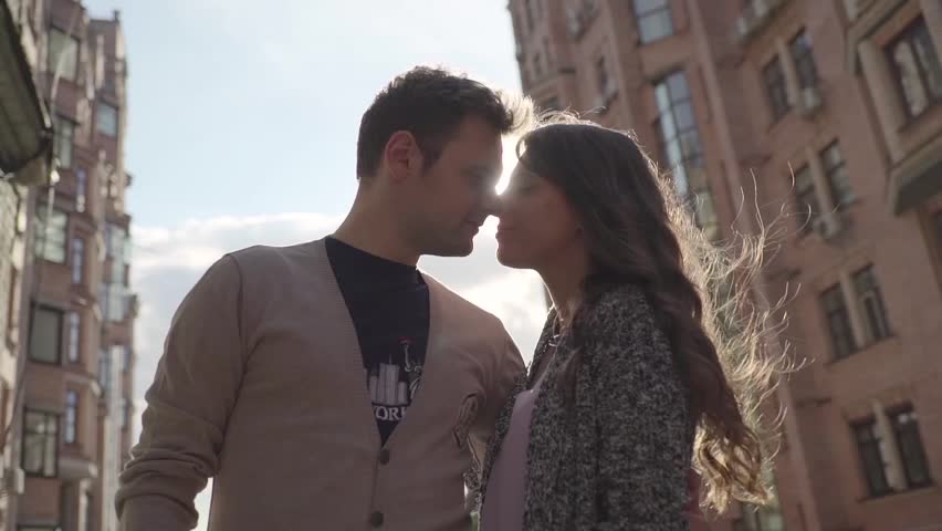 Couple hugging on the background of houses.