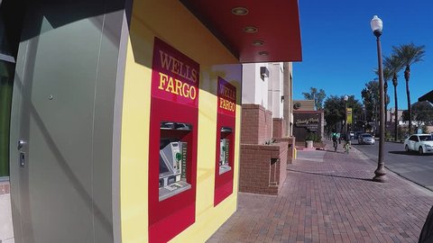 TEMPE, AZ/USA: January 30, 2017- Shot of a man as he approaches an ATM machine and inserts card. Guy is seen using a Wells Fargo cash machine.