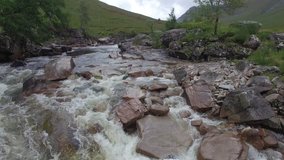 Aerial footage of a fast flowing bourne/creek in Glen Etive, Scottish Highlands, United Kingdom
