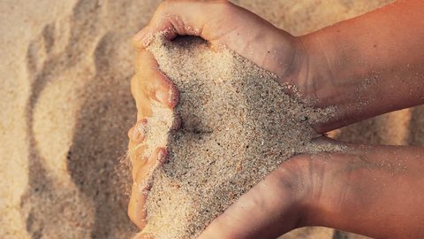Close up view of sand in the hands of women. The concept of the passing time of life