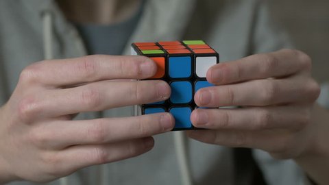 Boys hands solving rubik cube and showing thumb.