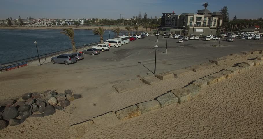 Drone video of view of Namibian Atlantic coastline, Swakopmund town buildings, beach, old pier, surf break point and landscape of ocean background of Swakopmund holiday resort at Namibia