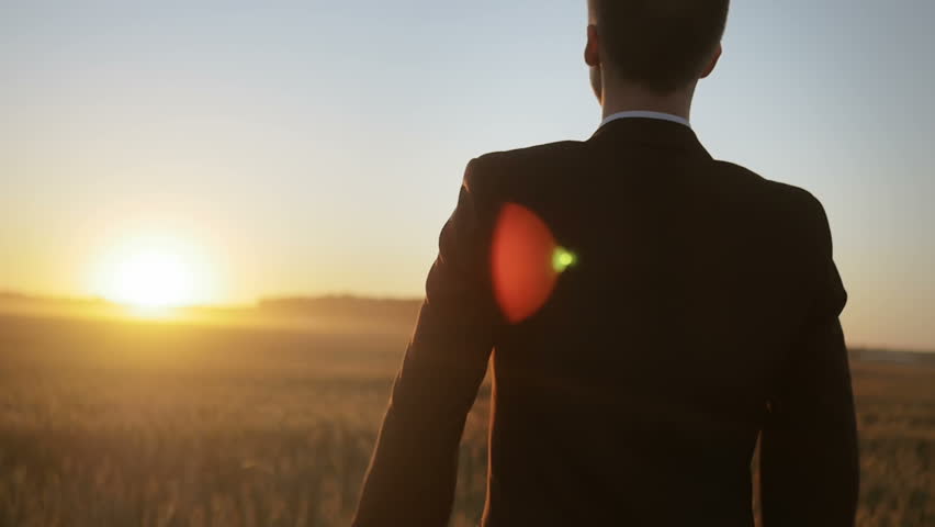 Slow motion of man in suit raising his hands up against the sun. Young man feeling a sense of accomplishment. Royalty-Free Stock Footage #24130114
