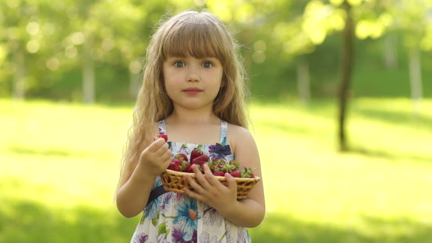 Girl eating strawberries and looking at camera

