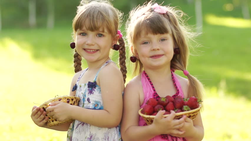 Little sister with strawberries in the hands
