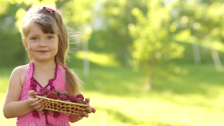 Girl holding basket of strawberries outdoors
