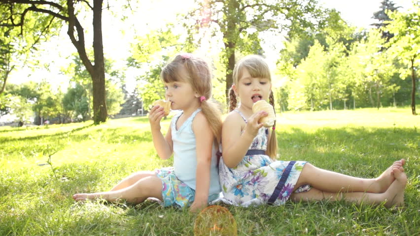 Children eating ice cream. Sitting on the grass
