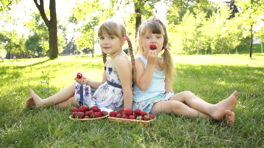 Happy girls eating strawberries. Sitting on the grass. Dolly HD
