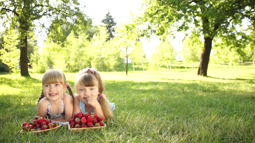 Children lying on the grass with strawberries
