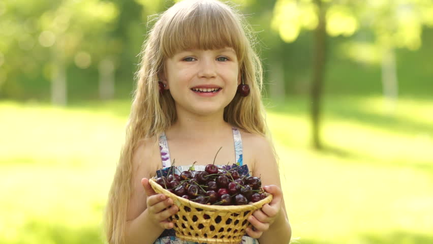 Child holding a basket of cherries in the hands
