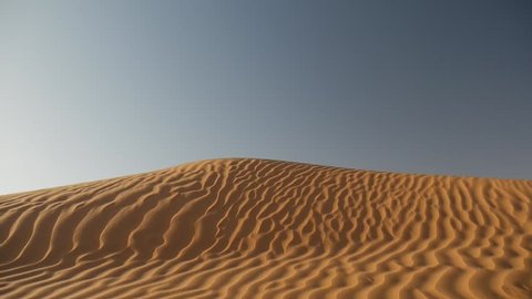 SAHARA DESERT, TUNISIA - CIRCA OCTOBER 2015:  a man walks barefoot on the fine sand of a dune in the Sahara desert in a sunny day.
