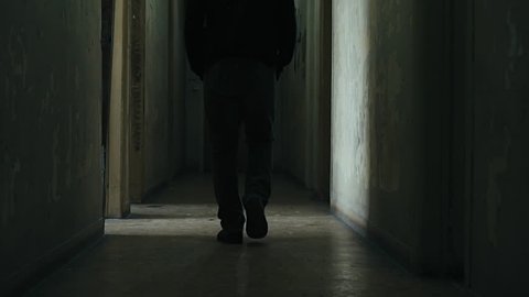 .Following a hooded young man inside a dark derelict ghetto building.A hooded young man facing social issues,walking inside a big apartment building in the projects in 100fps slow motion.Camera gimbal
