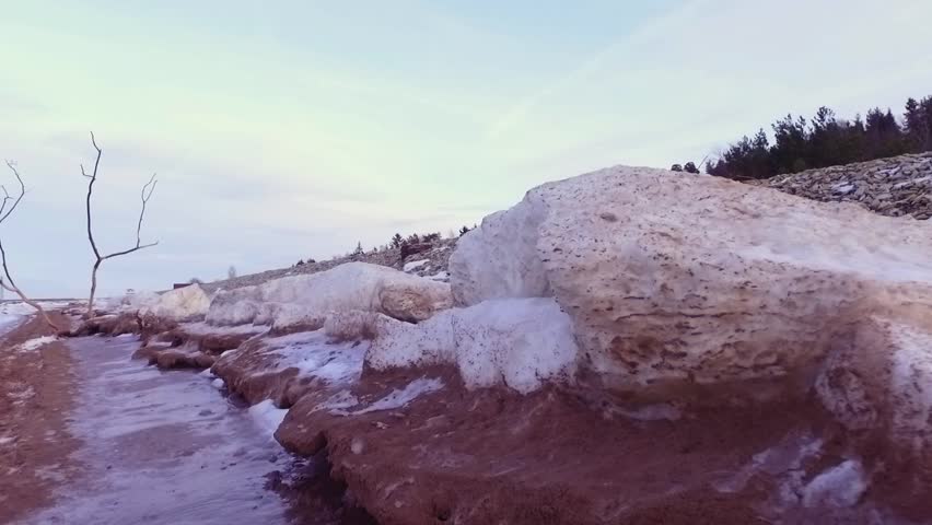 Frozen rock pools on the beach at winter coastal scene. Steadicam footage. Slow motion.