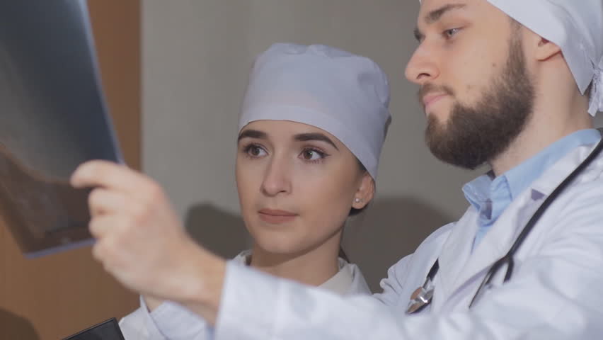 Doctor examines a colleague of x-ray image and explains that it is necessary to appoint a patient