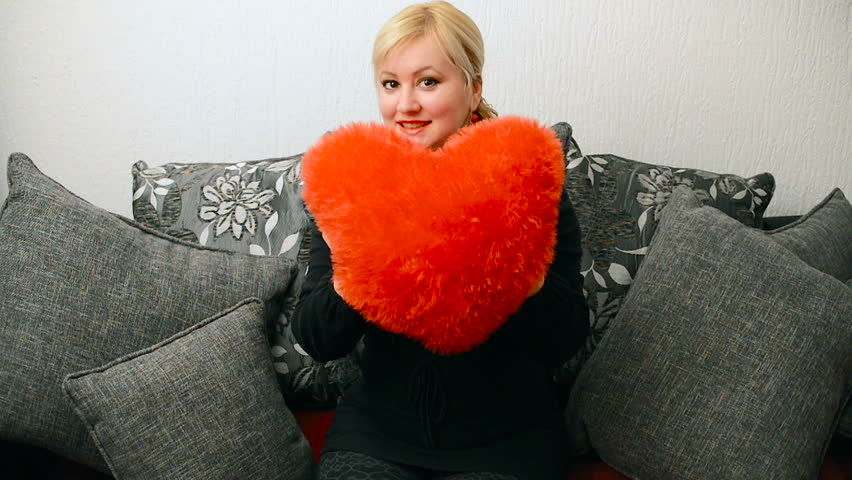 Blonde woman with red pillow heart shaped. Saint Valentine and International Women
