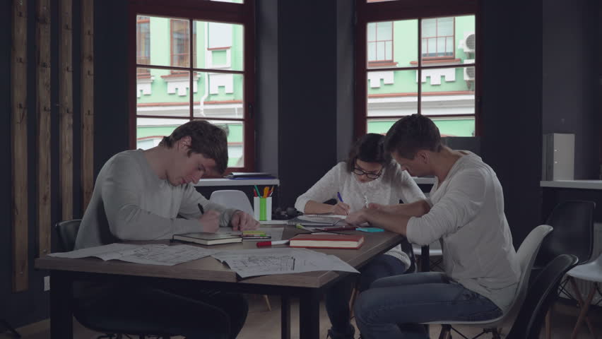 Staff sitting at the working place writing or filling some paper documents in modern stylish office. Young caucasian business people write handwriting report or request or application for