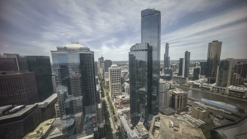 An aerial view of Melbourne cityscape including Yarra River and Victoria Harbour in the distance. Cloudscape time lapse during day light time with moving clouds. 