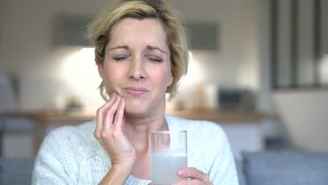 Middle-aged woman taking tylenol to ease toothache
