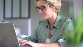 Portrait of blond woman working from home on laptop computer