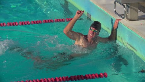 Swimmer in Front Crawl Race hit the wall first and turns to celebrate being number one.