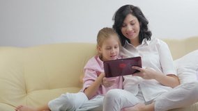 Mother with daughter using tablet computer, laughing and looking in digital tablet.
