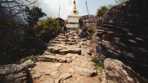 NACHIPANG, NEPAL - APRIL 16, 2016: Ascending the cobblestone road with white stupa on the top. The Himalaya. View of nepali prayer wheels