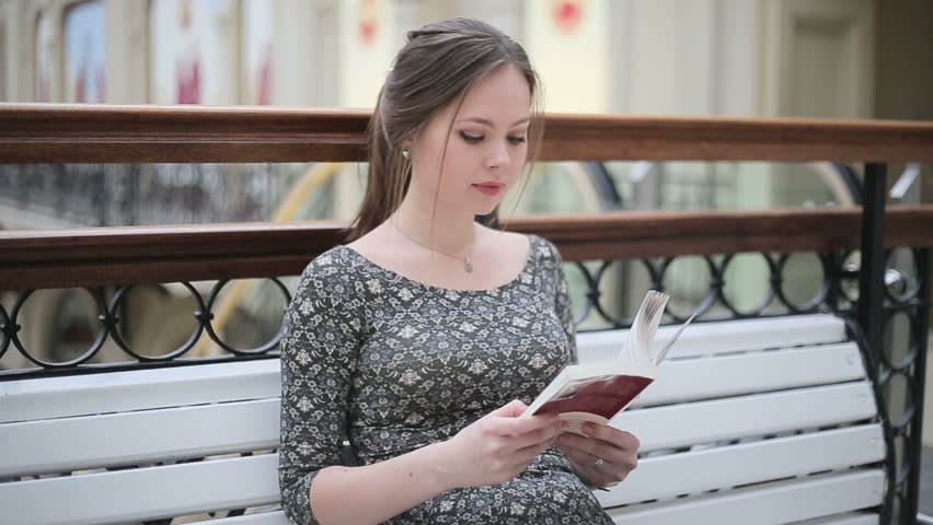 Young girl reading a book on bench