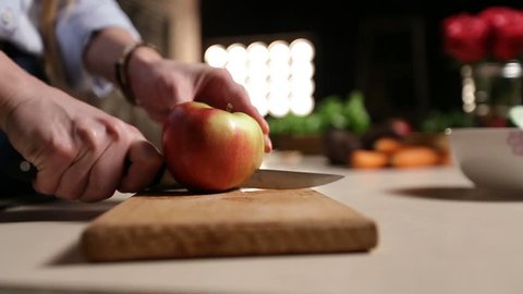 Woman with knife cutting apple on chopping board