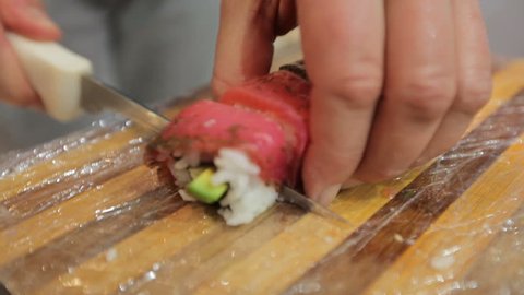 Sushi chef cutting sushi rolls