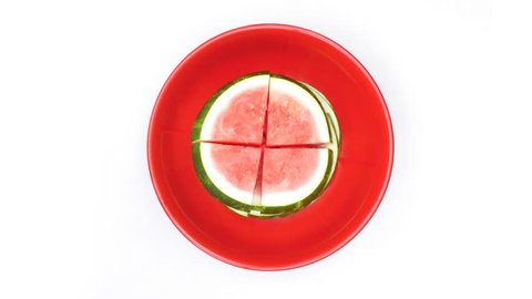 Time lapse of sliced watermelon being taken from bowl on white background.