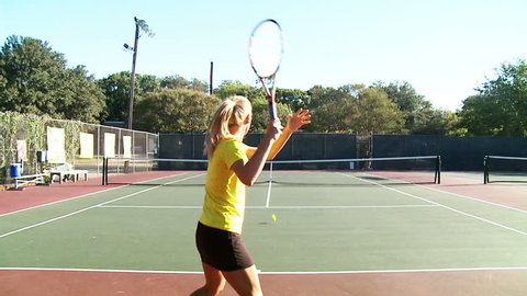 Slow motion of young women playing tennis. Zooming in and out to the ball.