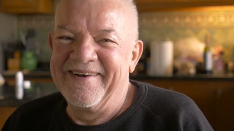 A happy retired baby boomer senior man smiles and laughs at the camera in slow motion
