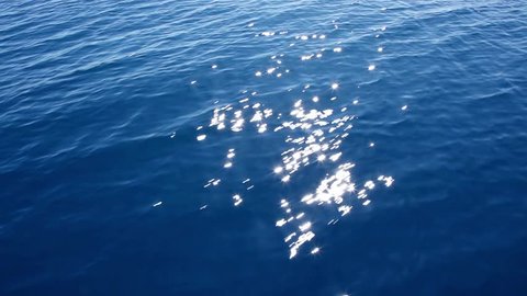 blue sea water passing view from a moving boat with sparkles and light reflections