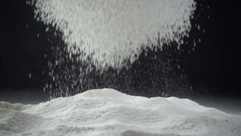 Sifting flour through sieve. Black background