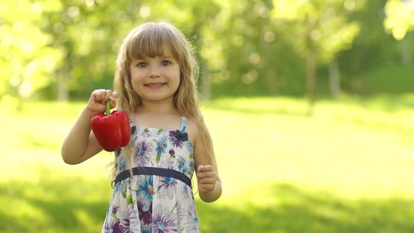 Portrait of a girl playing with a vegetable pepper. Looking at camera
