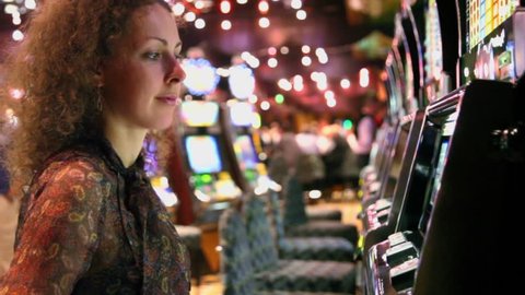Woman pushes buttons on play machine in casino and becomes very happy when she wins
