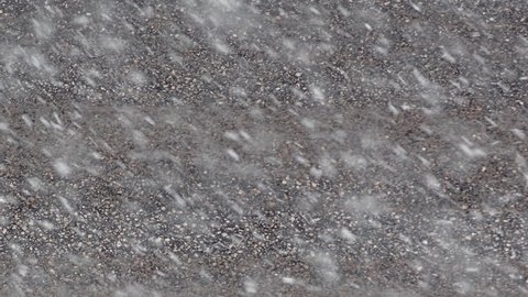 Winter storm. A detail of asphalt road in heavy snowfall. A two cars passing through.