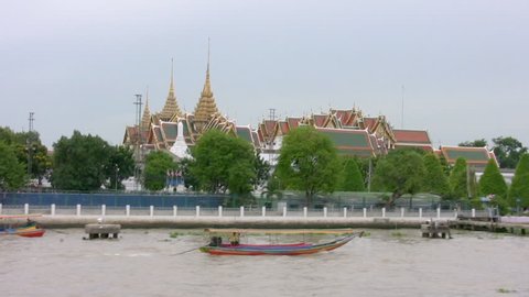 Passing Wat Phra Kaeo and the Grand Palace on the Chao Phraya River, Bangkok, Thailand. Longtail boat and military ferries moving past. Canon HV20, HD 1080-50i.