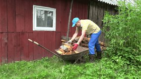 man loaded wood of wheelbarrows into a pile near house wall in village. video clip.