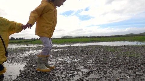 Kids in rain boots jumping happily in puddle