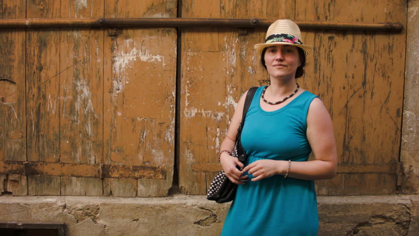 Woman in a hat smiling and posing on a background of the old wall