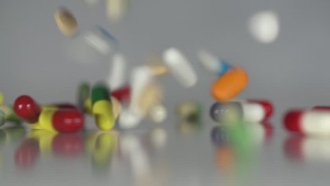 Raining Pills - Extreme close up of Medicine, drugs, pills, capsules falling in slow motion on a neutral background.