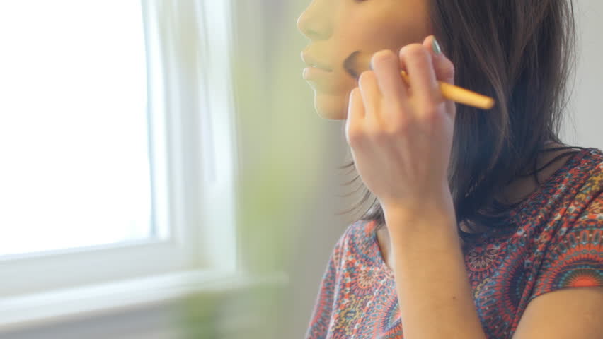 Stylish young woman applies makeup and looks at camera