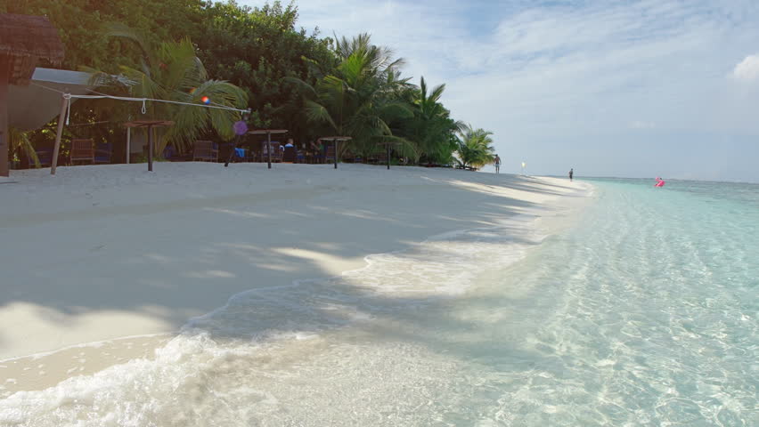 Gentle waves lap at the pristine. white sand of a tropical. luxury beach resort in the Maldives. with sound. 4k video