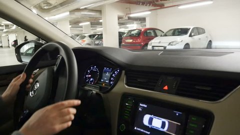 STRASBOURG, FRANCE - CIRCA 2017: Point of view of passenger at driver hands - woman parking Skoda car using the parkgronic parctronic parking assistant audio signal and visual aid - exit car
