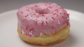 strawberry donut with colorful sprinkles on a plate. video rotation
