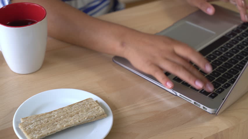Close up working place with laptop and mug with tea and healthy cereal snack.