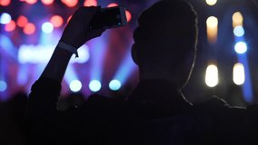 Happy man dancing and shooting video on smartphone at night club, concert